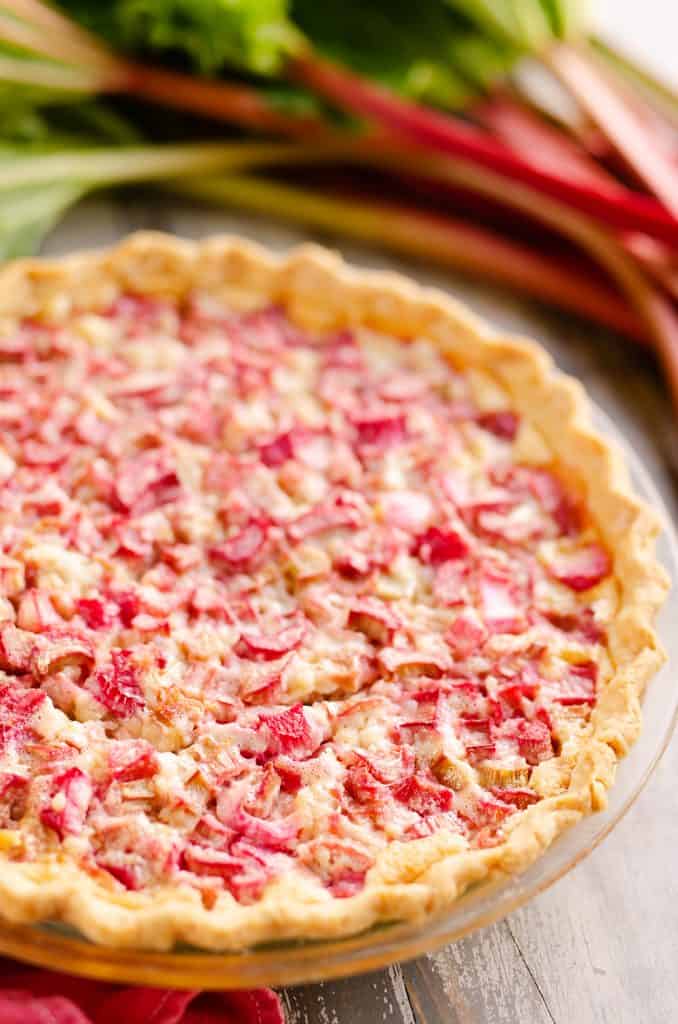 Rhubarb Custard Pie on table with stalks of rhubarb