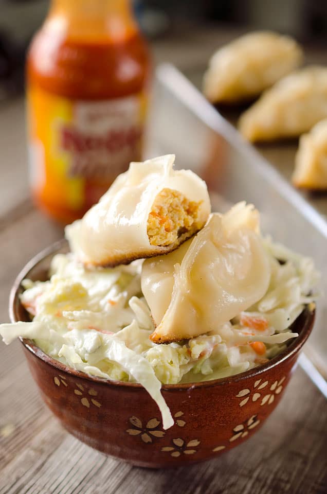 Buffalo Chicken Potstickers are a surprisingly easy and healthy dinner with chewy wrappers filled with lean ground chicken, vegetables and buffalo sauce served over a crunchy bleu cheese broccoli slaw.