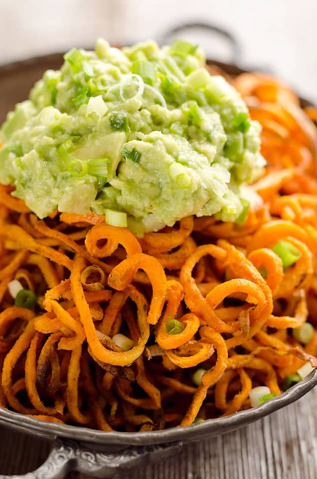 Spicy Roasted Sweet Potato Spirals with Guacamole is an amazingly delicious meatless dinner or appetizer with crispy sweet potatoes coated in garlic & chili powder and topped with a zesty guacamole.