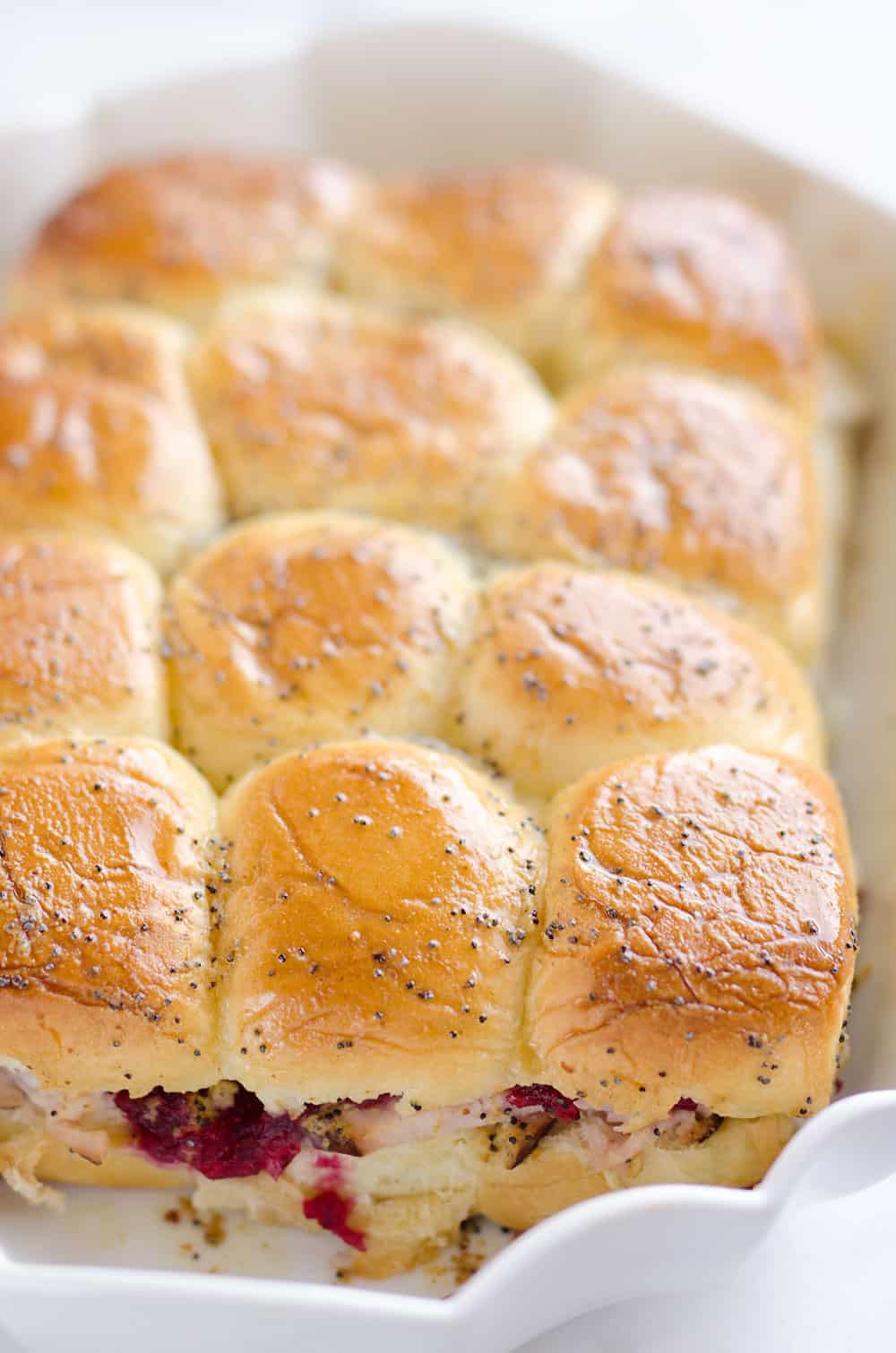 Cheesy Cranberry Turkey Baked Sliders are a quick and easy recipe to use up some of that leftover turkey and cranberries from the holidays! Hawaiian rolls are topped with turkey, cranberries and Havarti cheese and topped with a savory butter sauce for a great dinner after the big meal.