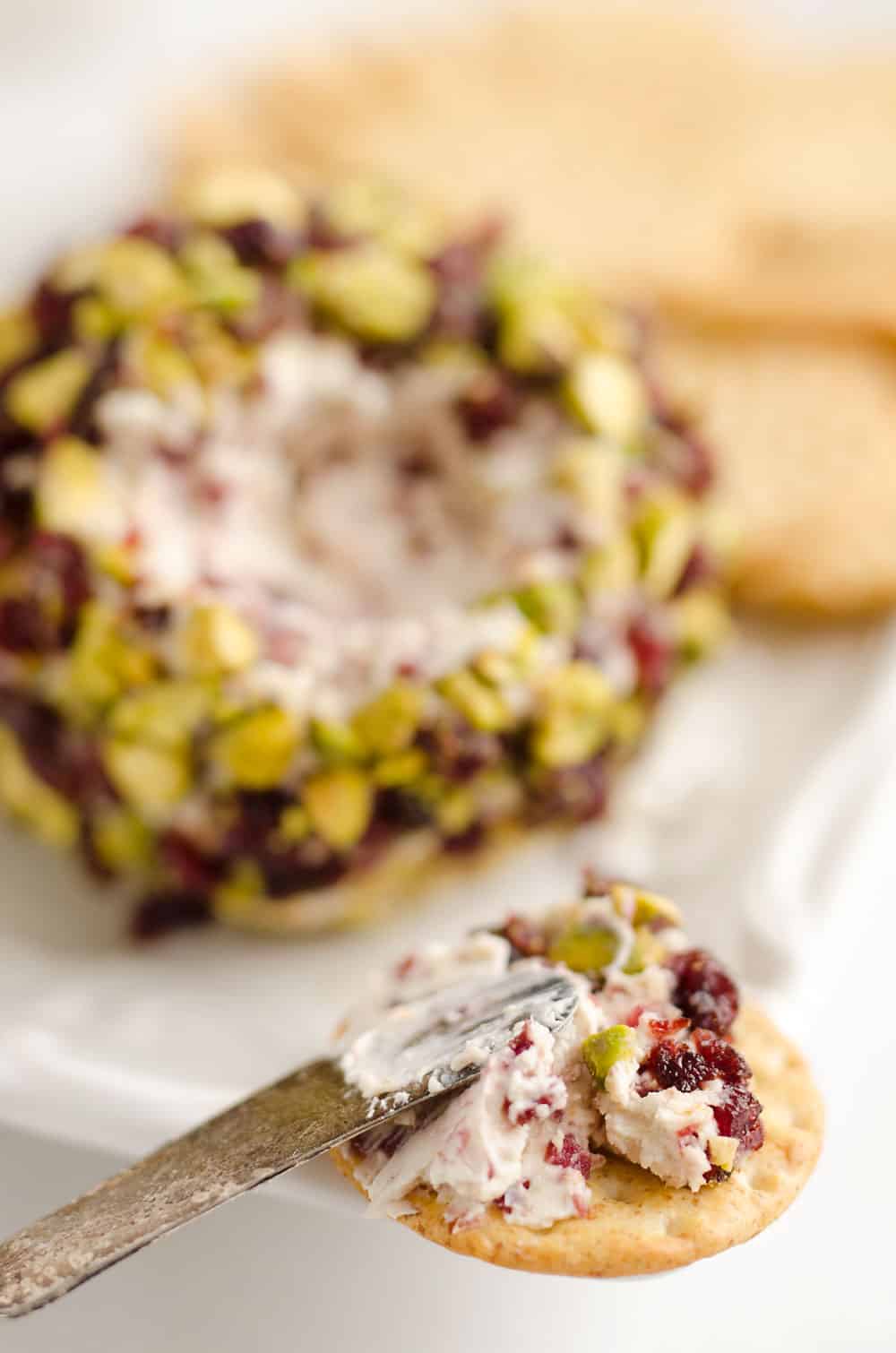 Cranberry Pistachio Cheese Ball is a festive red and green appetizer fantastic for the holidays! A cream cheese and cranberry mixture is rolled in salty pistachios and served with your favorite crackers for the perfect party food.