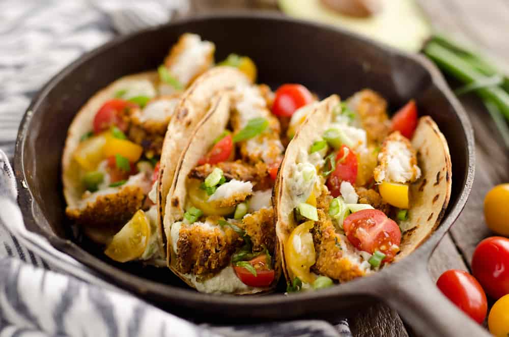 Tortilla Crusted Fish Tacos with Avocado Crema are a healthy and easy weeknight meal you can make in just 20 minutes with your Airfryer! Crispy Tortilla Crusted Tilapia is layered in a grilled corn tortilla with avocado crema and fresh tomatoes for a flavorful dinner recipe the whole family will love.