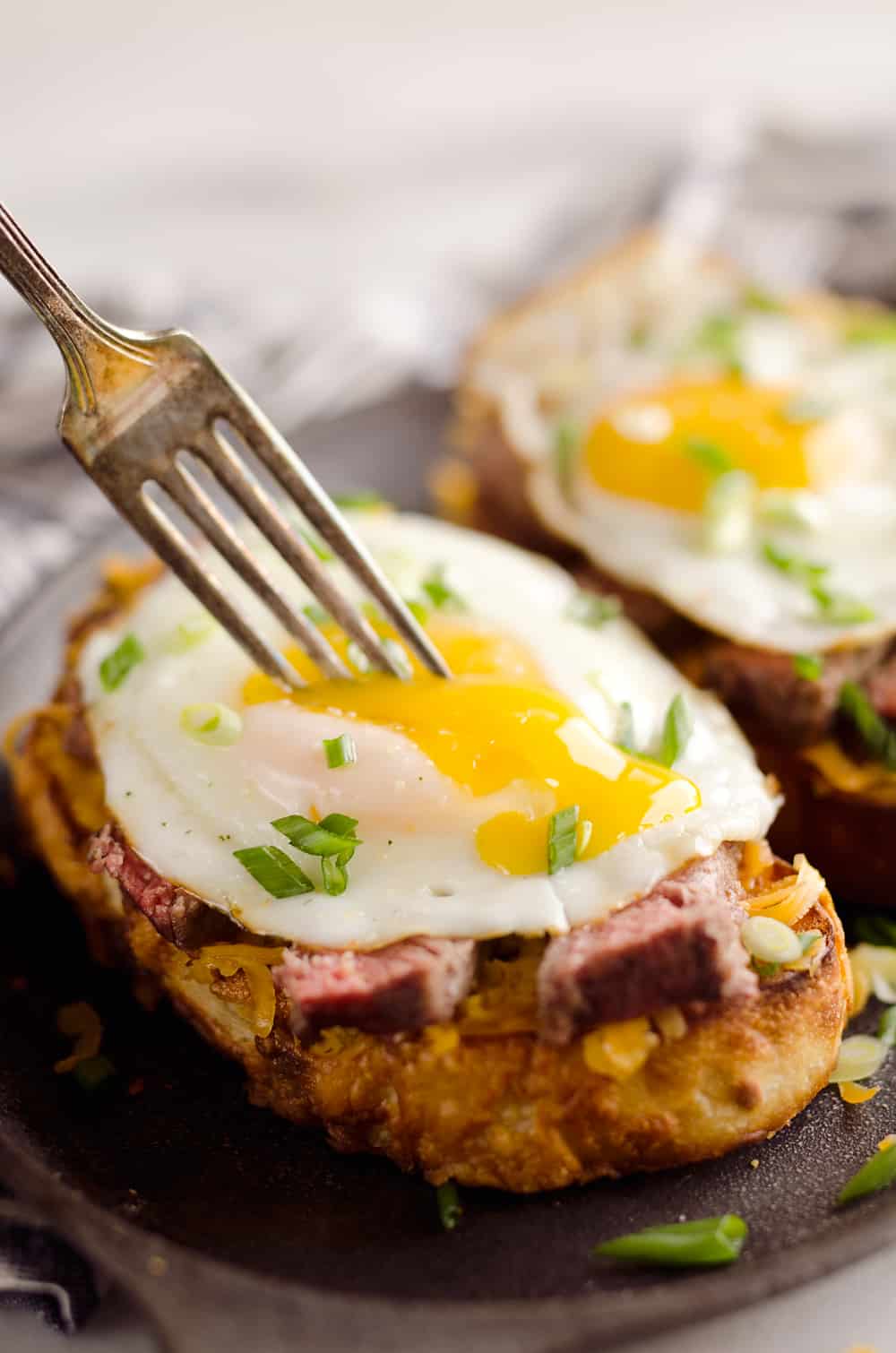 Breakfast Steak & Cheddar Toasts are a rich and decadent recipe filled with all the best parts of brunch. Tender steak is layered on top of a cheesy toast and topped with a sunny side up egg and scallions.