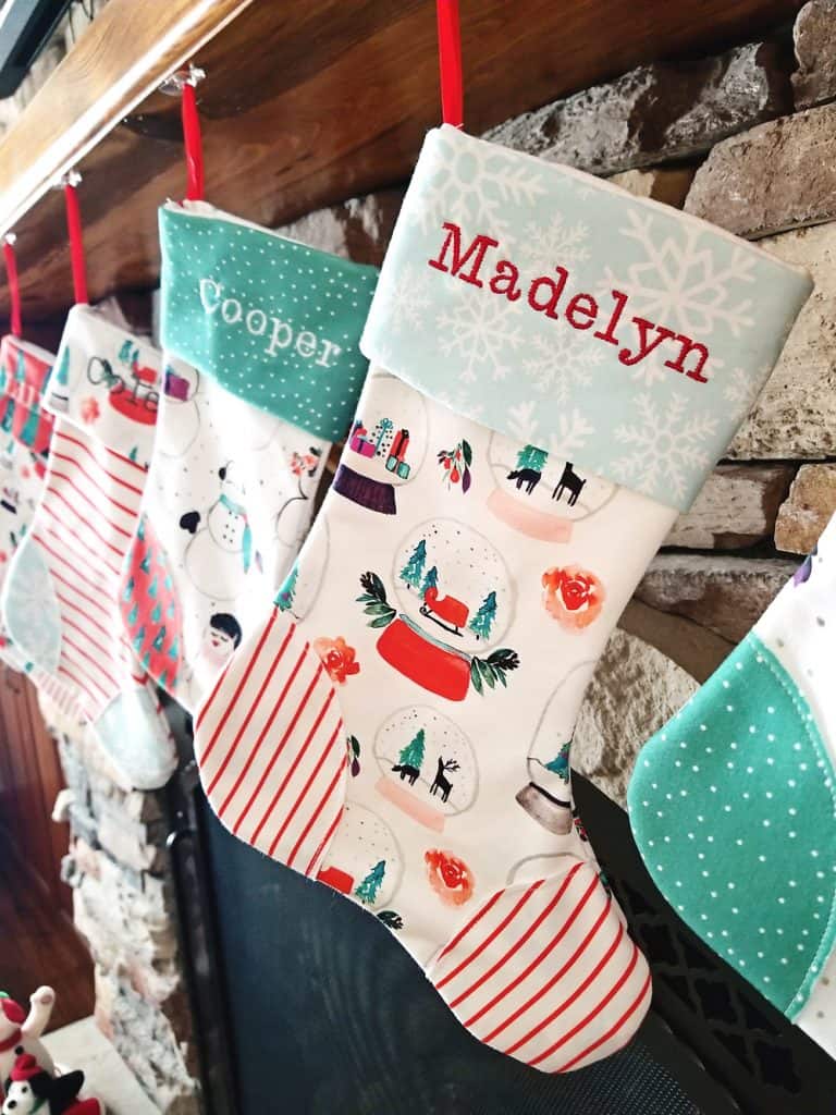 homemade personalized Christmas stockings hanging on fireplace mantel