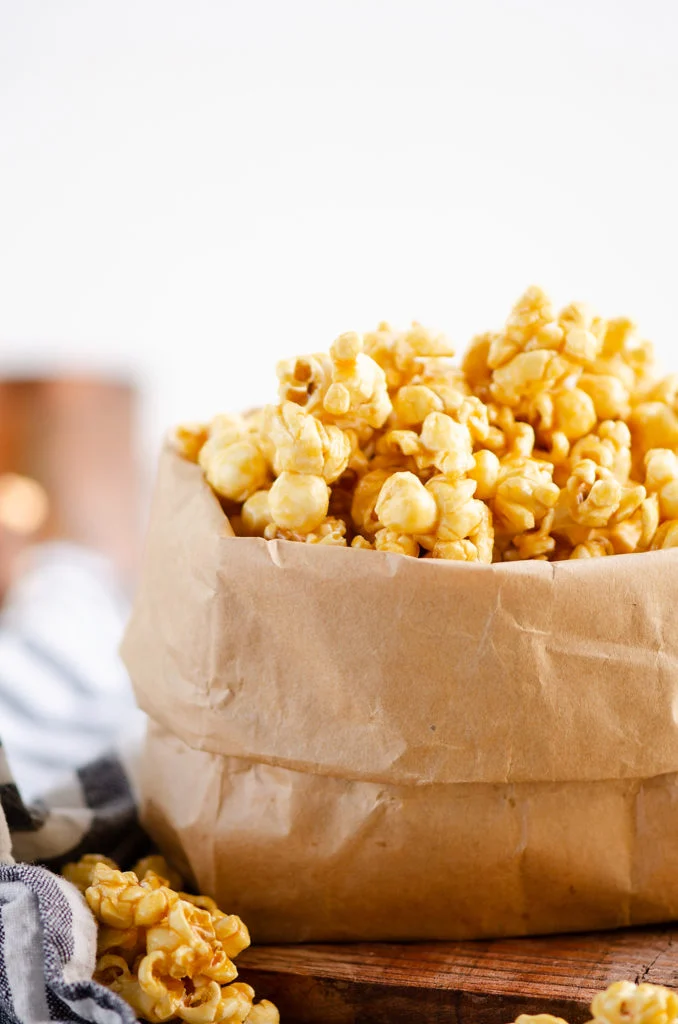 Microwave Caramel Popcorn in a brown paper bag with measuring cup