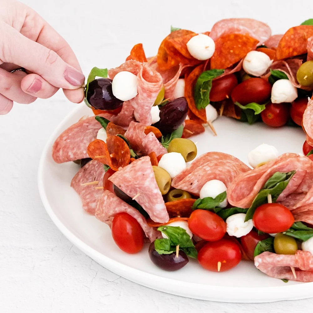christmas wreath appetizer on plate with skewers of meat and cheese
