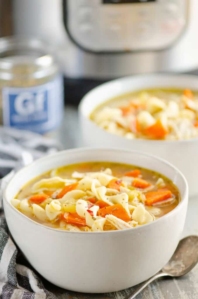 bowl of Greek chicken noodle soup in bowl by Instant Pot on table