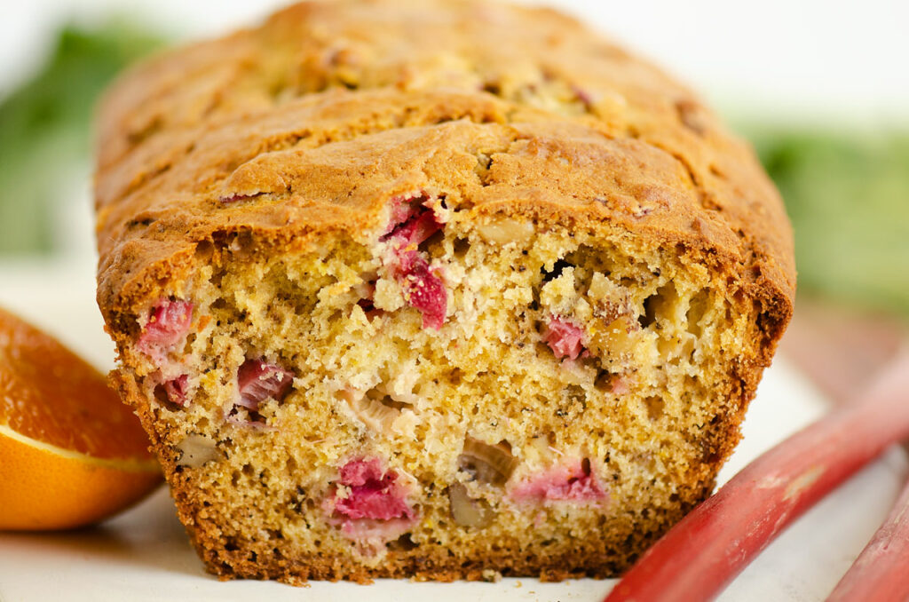 rhubarb walnut bread on table with rhubarb stalks and oranges