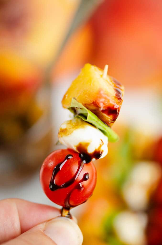 peach, basil, mozzarella and tomato on toothpick with balsamic glaze drizzle